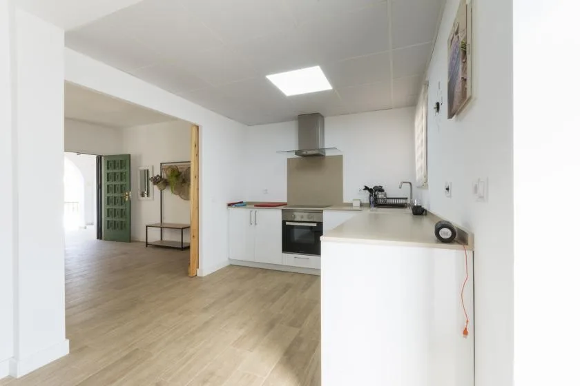 An open kitchen with white cabinets and light wood flooring.
