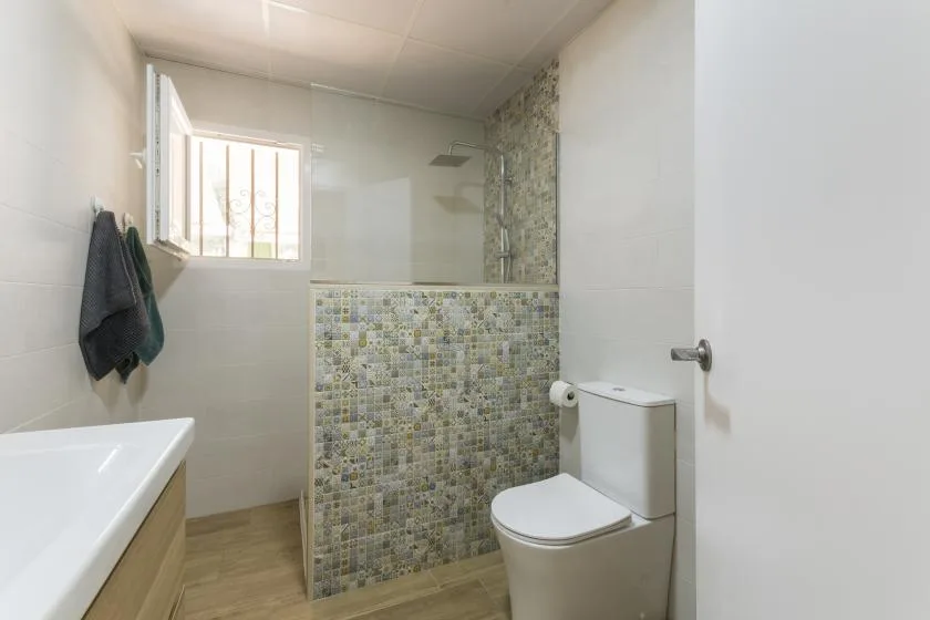 A bathroom with a tiled shower area and a toilet.
