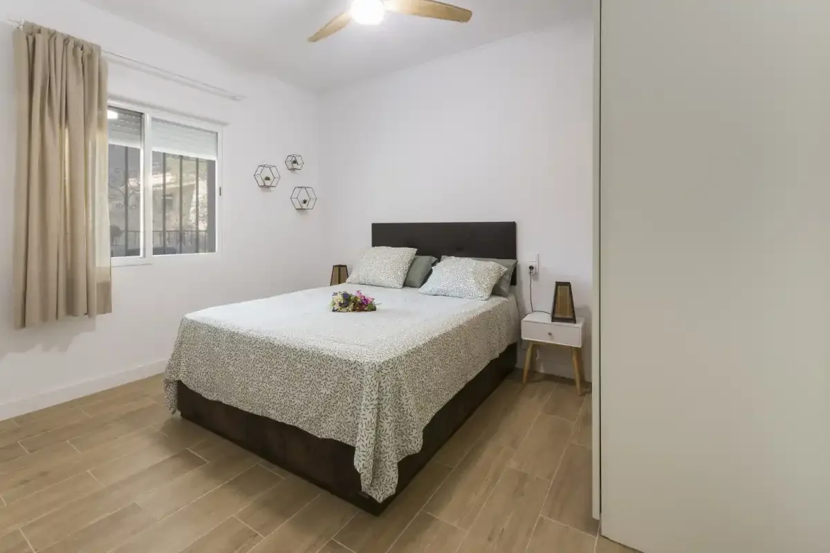 A bedroom with a double bed, bedside tables, and a window.