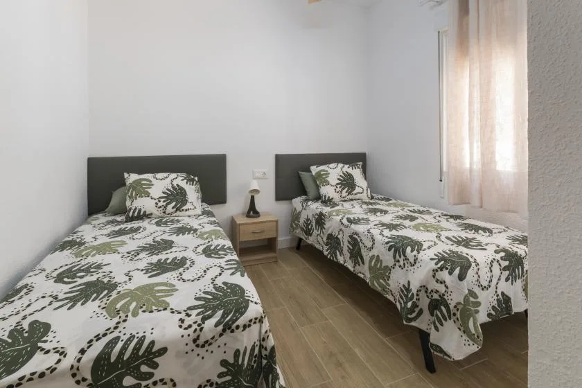 A bedroom with two beds dressed in patterned bedding.
