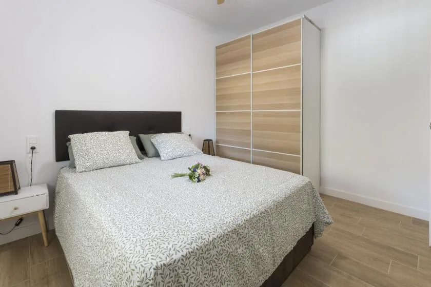 A bedroom with a double bed and a wood-toned wardrobe.
