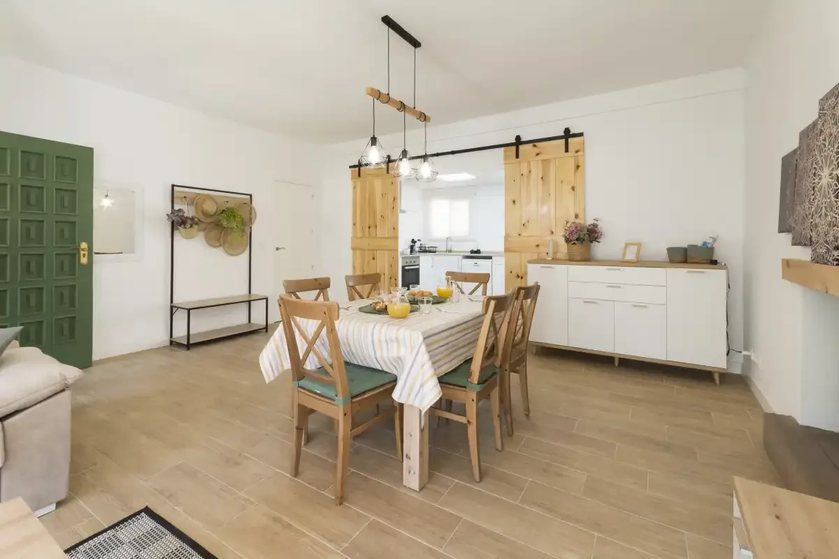 A dining area with a table and chairs beside a bright kitchen.