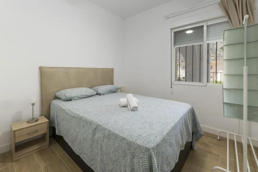 A bedroom with a double bed, bedside table, and window.