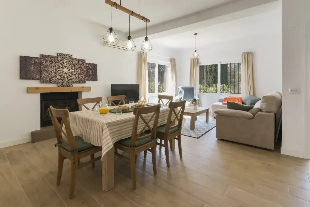 A dining area with a table and chairs opens onto a living room with a sofa.