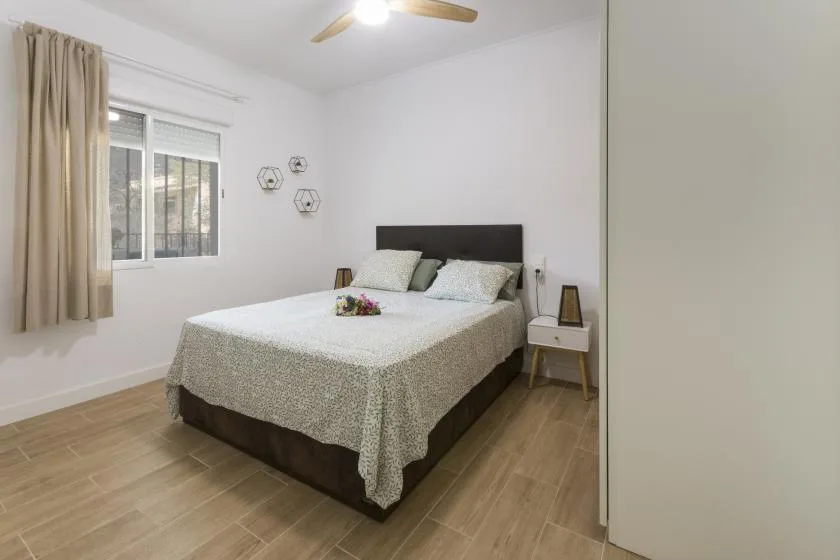A bedroom with a bed, window, and light wood flooring.