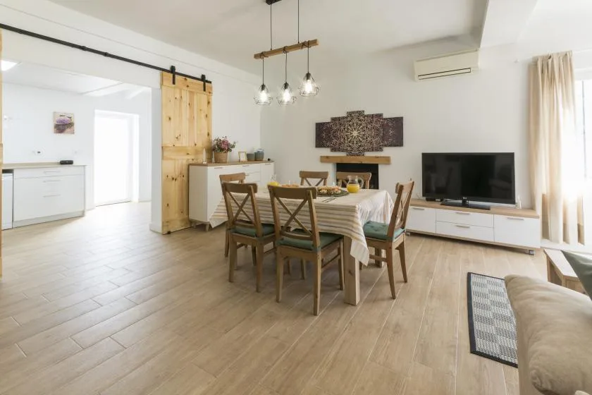 A bright open-plan living and dining area with a table and television.
