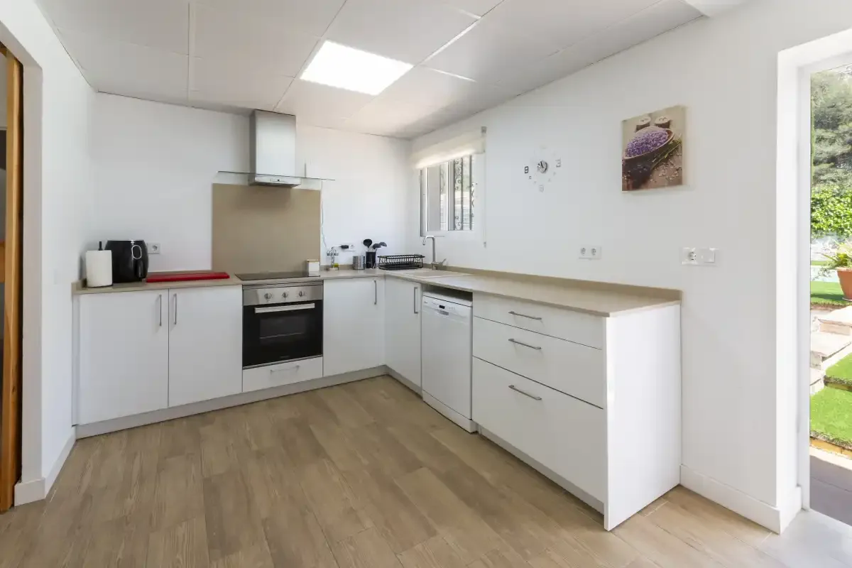 A bright kitchen with white cabinets, countertops, and a built-in oven.