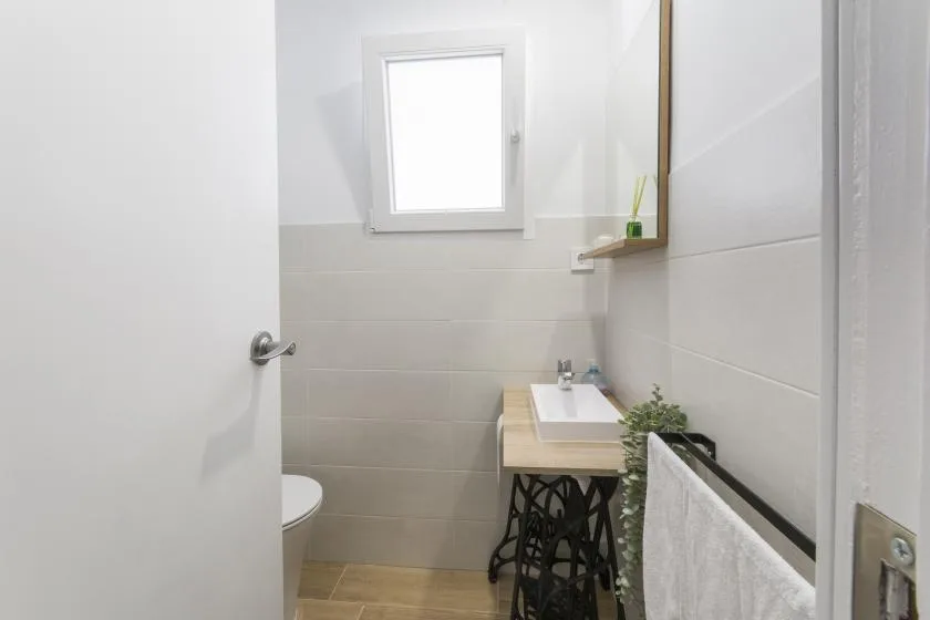 A compact bathroom with a sink, toilet, and small window.