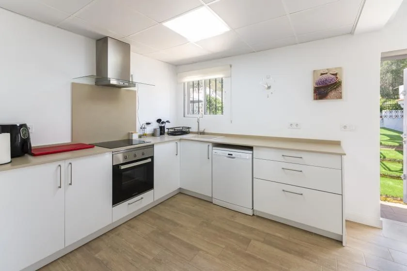 A bright kitchen with white cabinets, a built-in oven, and a window.