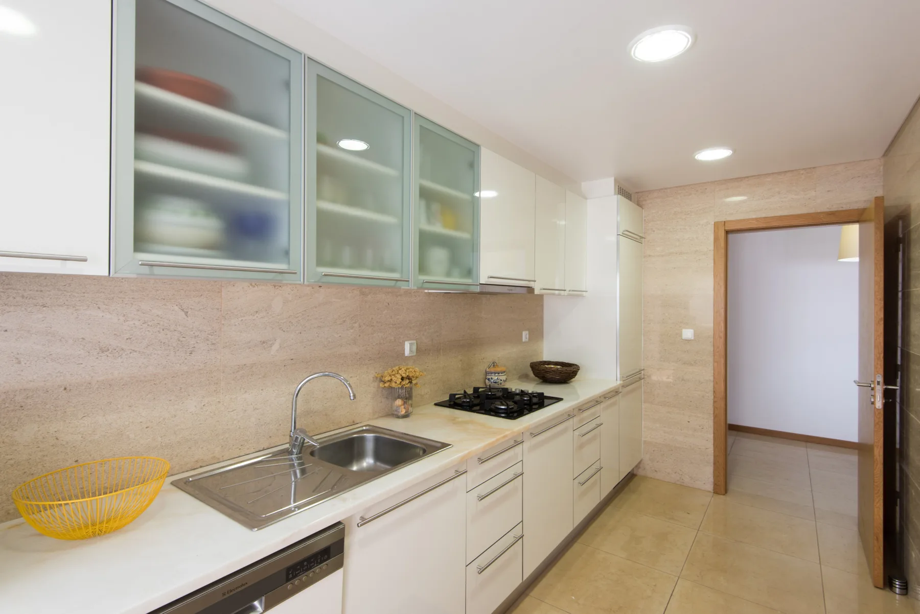 A bright kitchen with pale cabinets, a countertop, and a cooking area.