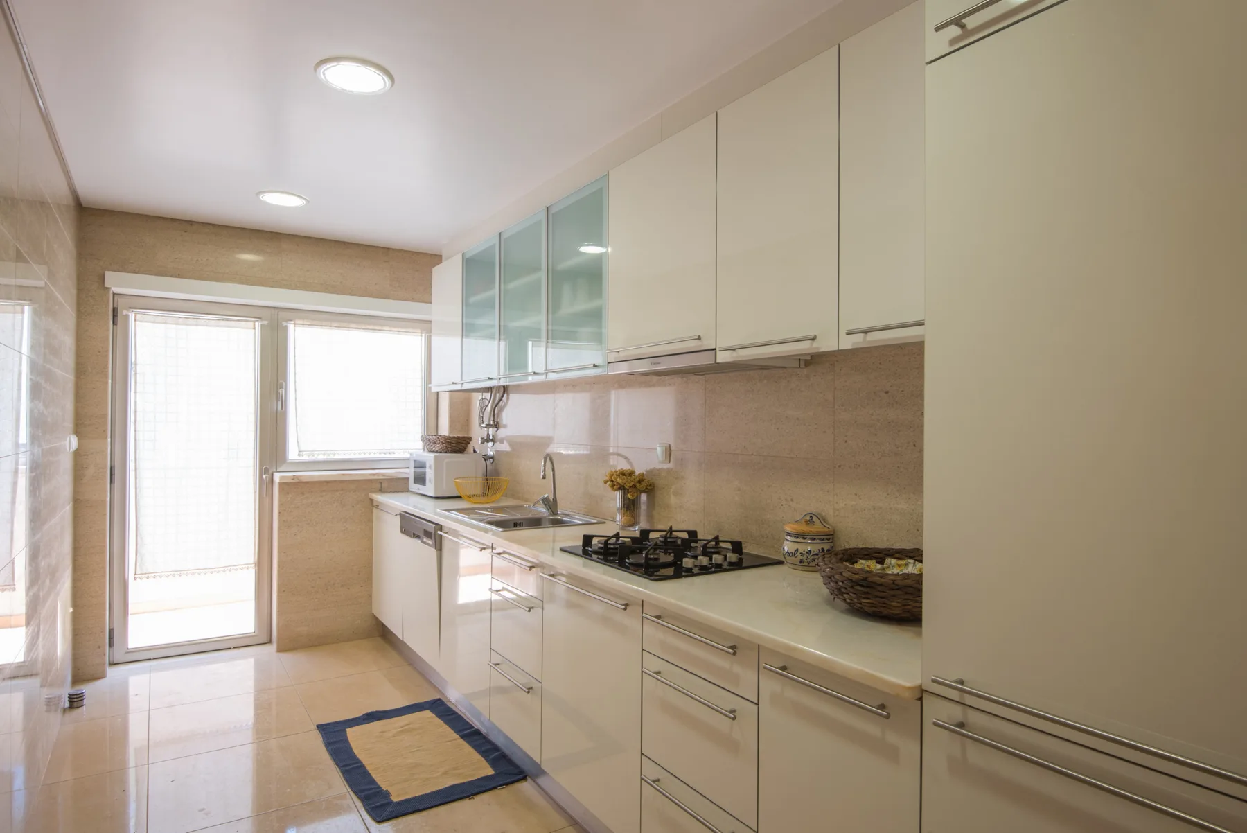 Una cocina luminosa con armarios blancos, una encimera y una placa de gas.