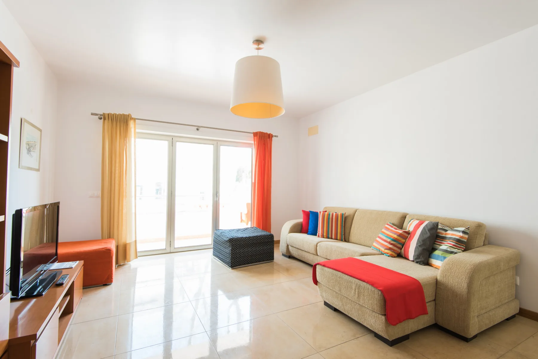 A bright living room with seating, a television, and sliding glass doors.