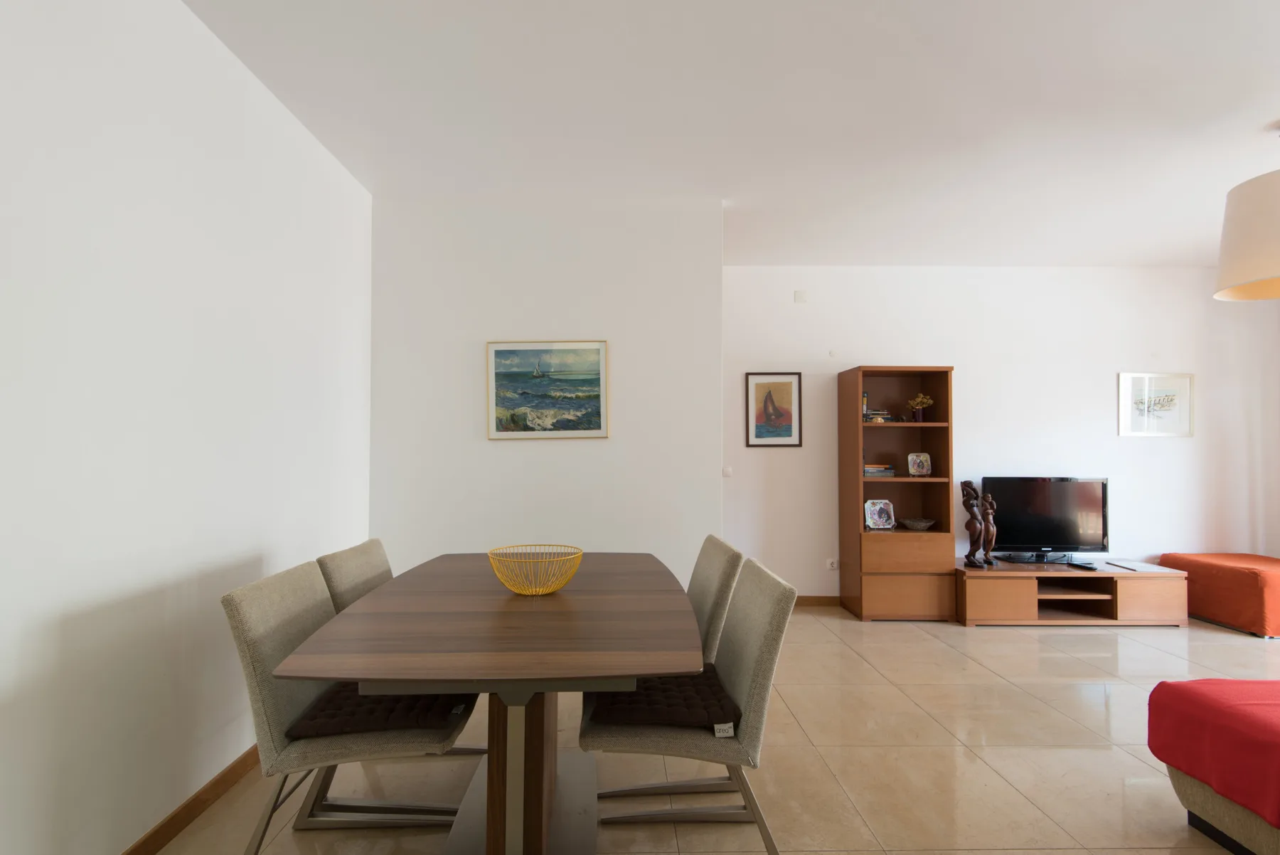 A dining area with a table and seating beside a living area with a television.
