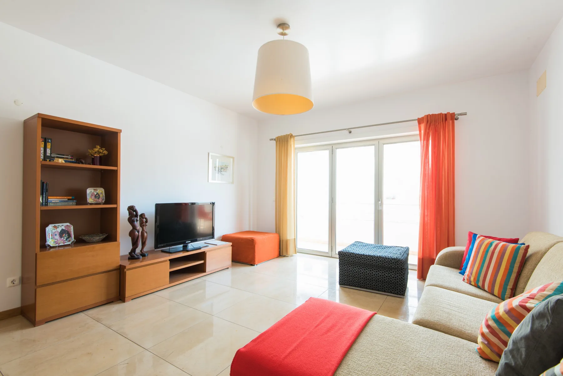 A living room with seating, a television, and bright windows.