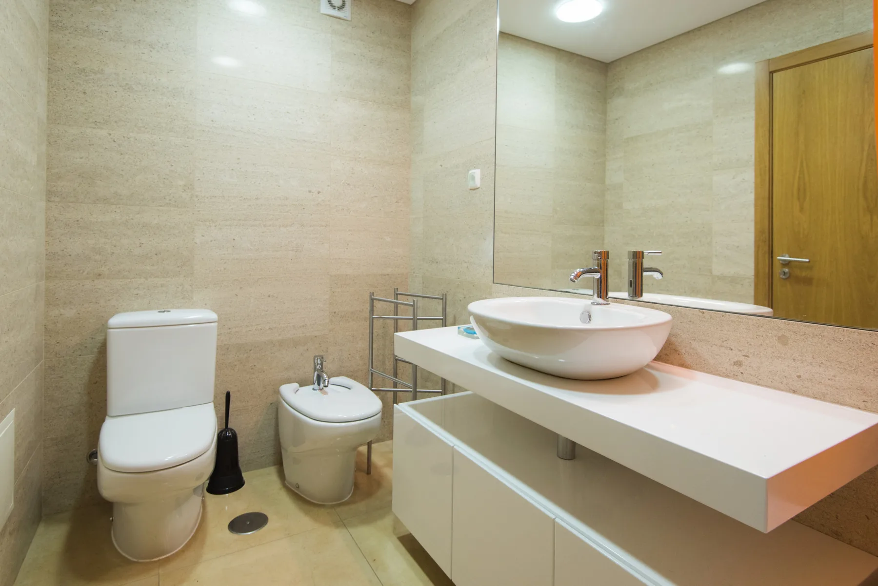 A bathroom with a sink, toilet, and bidet.