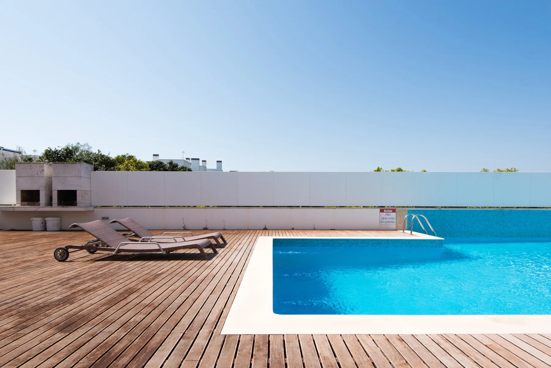 A rooftop pool beside a wooden deck with lounge seating.