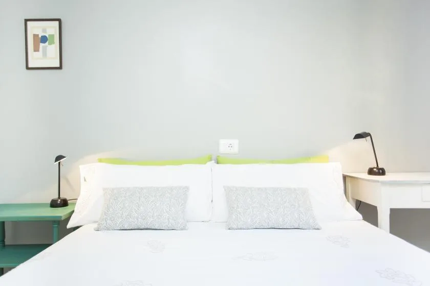 Un dormitorio con una cama blanca y mesitas de noche a juego.