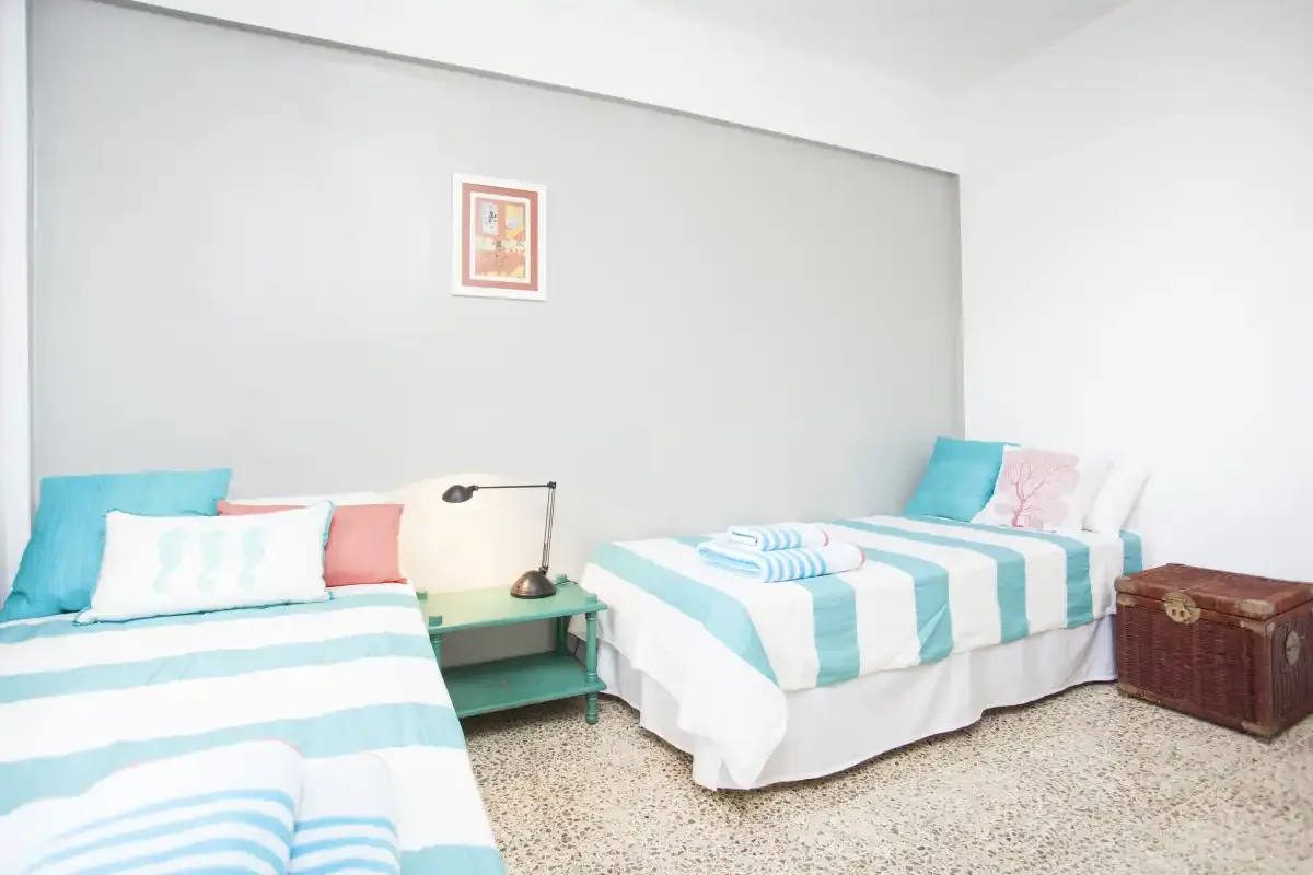 Un dormitorio con dos camas vestidas con ropa de cama blanca y turquesa.