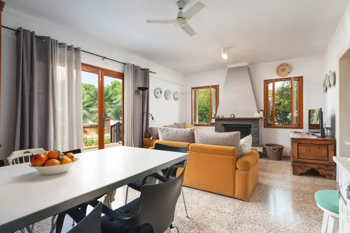 Una luminosa sala de estar y comedor con asientos, una mesa y grandes ventanas.