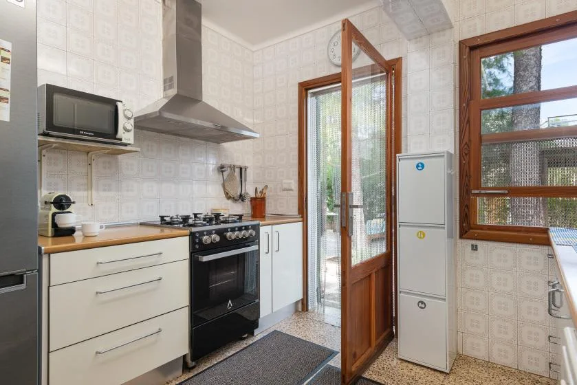 Una cocina con estufa, encimera y una puerta de vidrio que da al exterior.