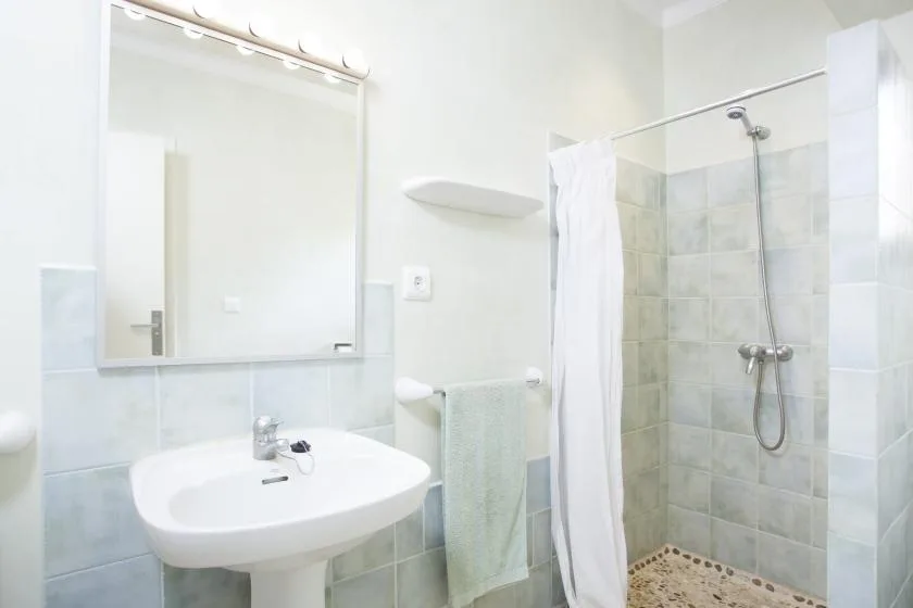 Un baño luminoso con lavabo, espejo y ducha con cortina.