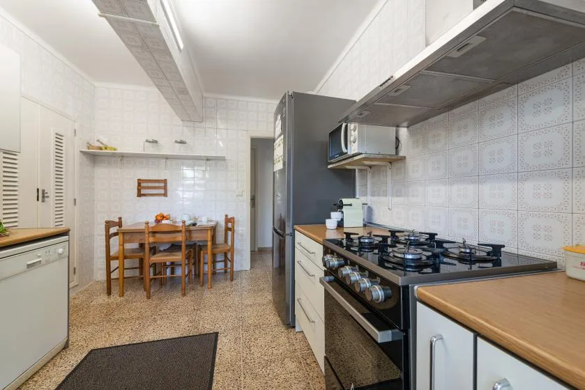 Una cocina alicatada con una estufa de gas y una mesa de comedor en la zona contigua.
