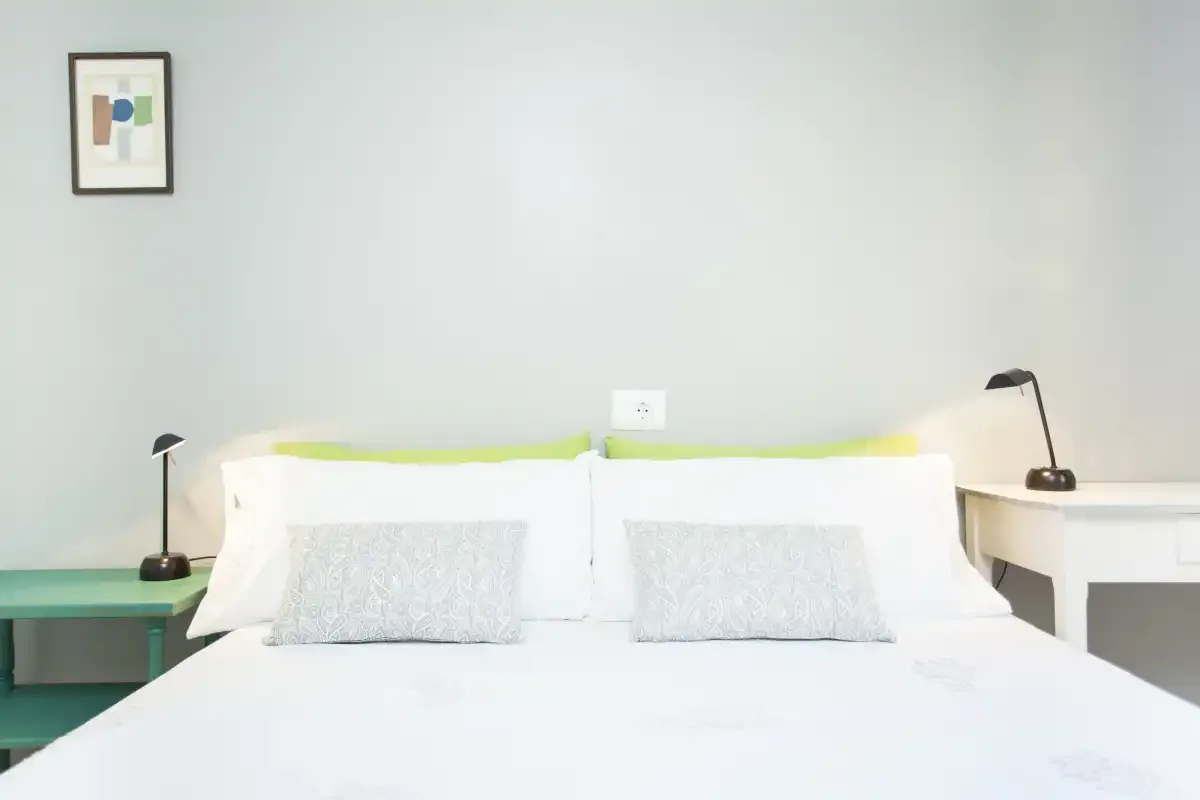 Un dormitorio luminoso con una cama bien tendida y lámparas de mesilla a juego.