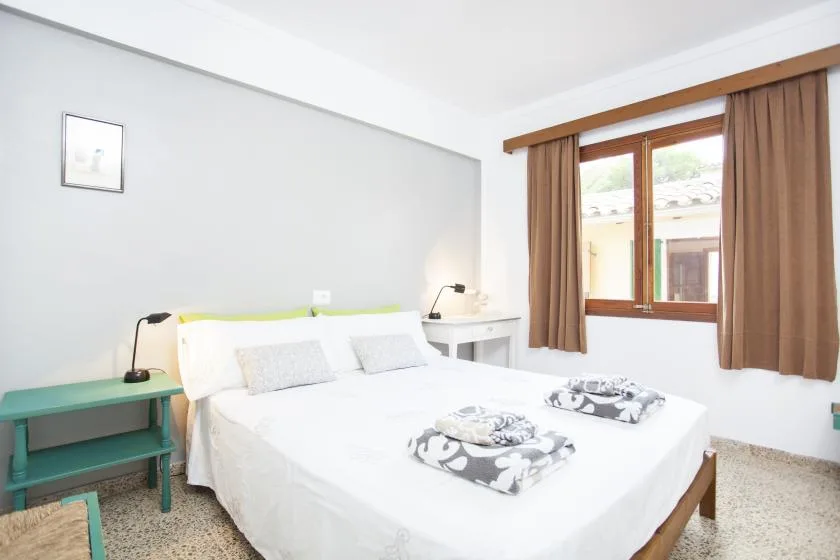 Un dormitorio con una cama blanca y una ventana enmarcada por cortinas marrones.