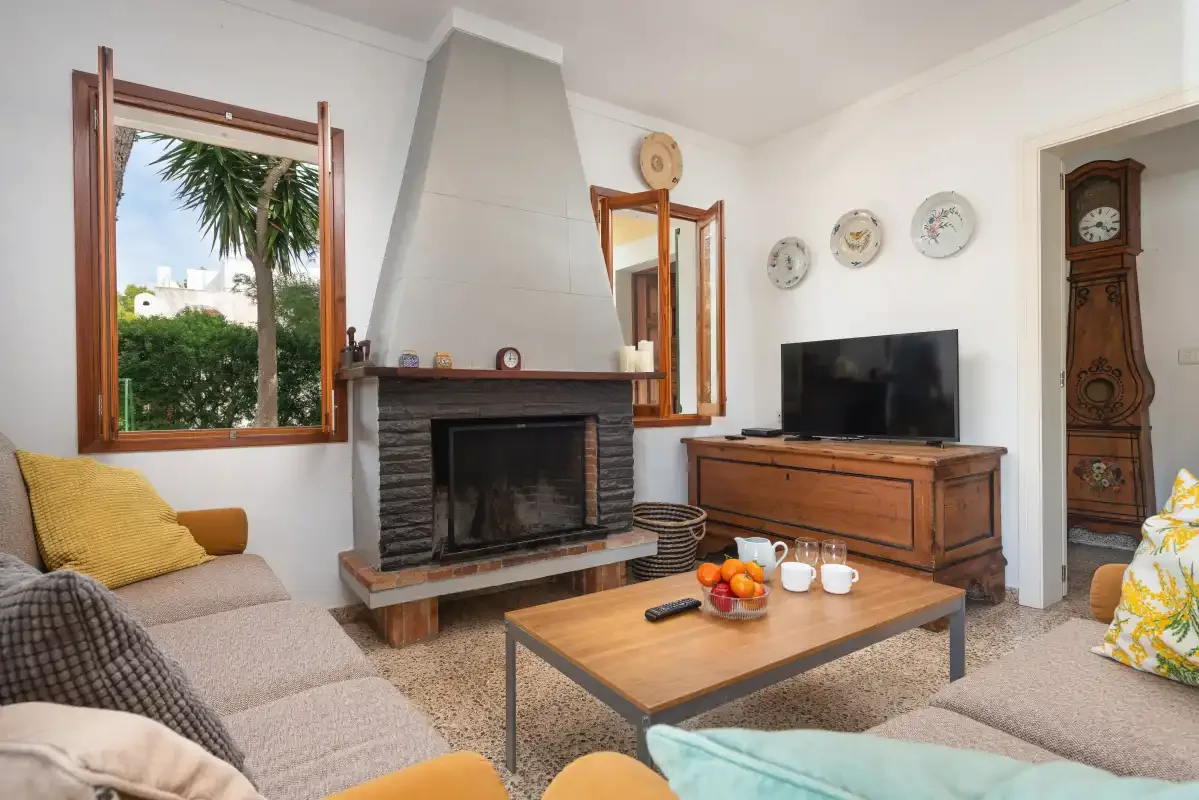Un salón luminoso con chimenea, televisión y asientos.