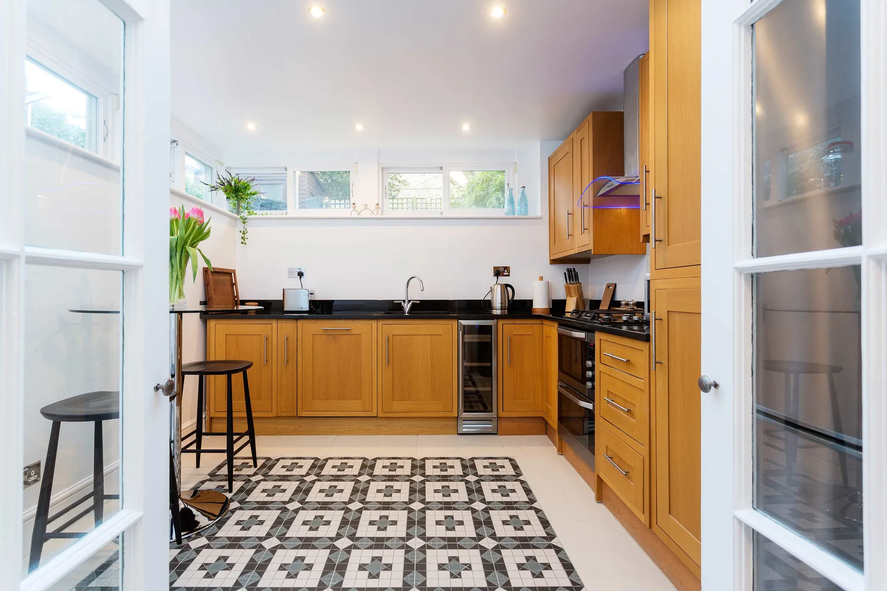 A bright kitchen with wooden cabinets, dark countertops, and a patterned floor.