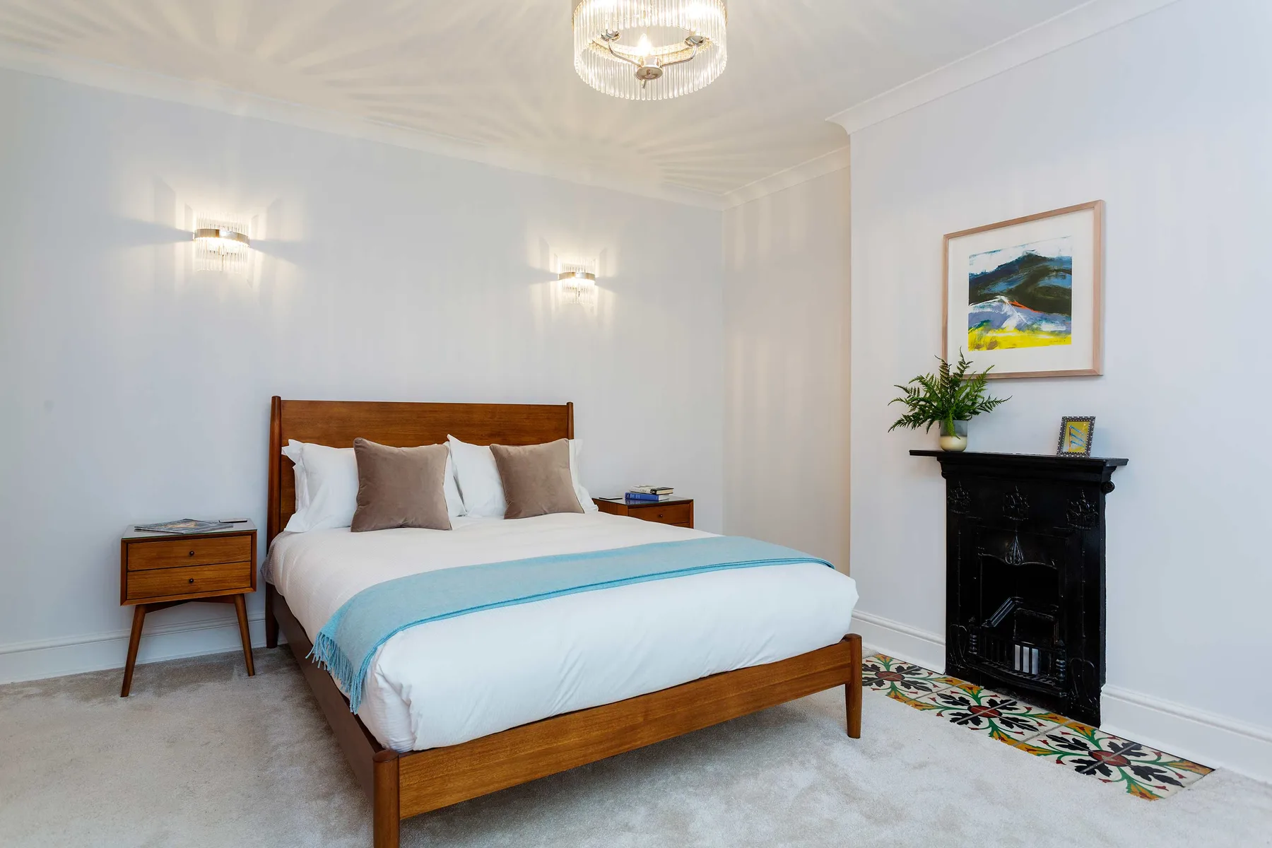 A bedroom with a wooden bed, pale bedding, and a fireplace.