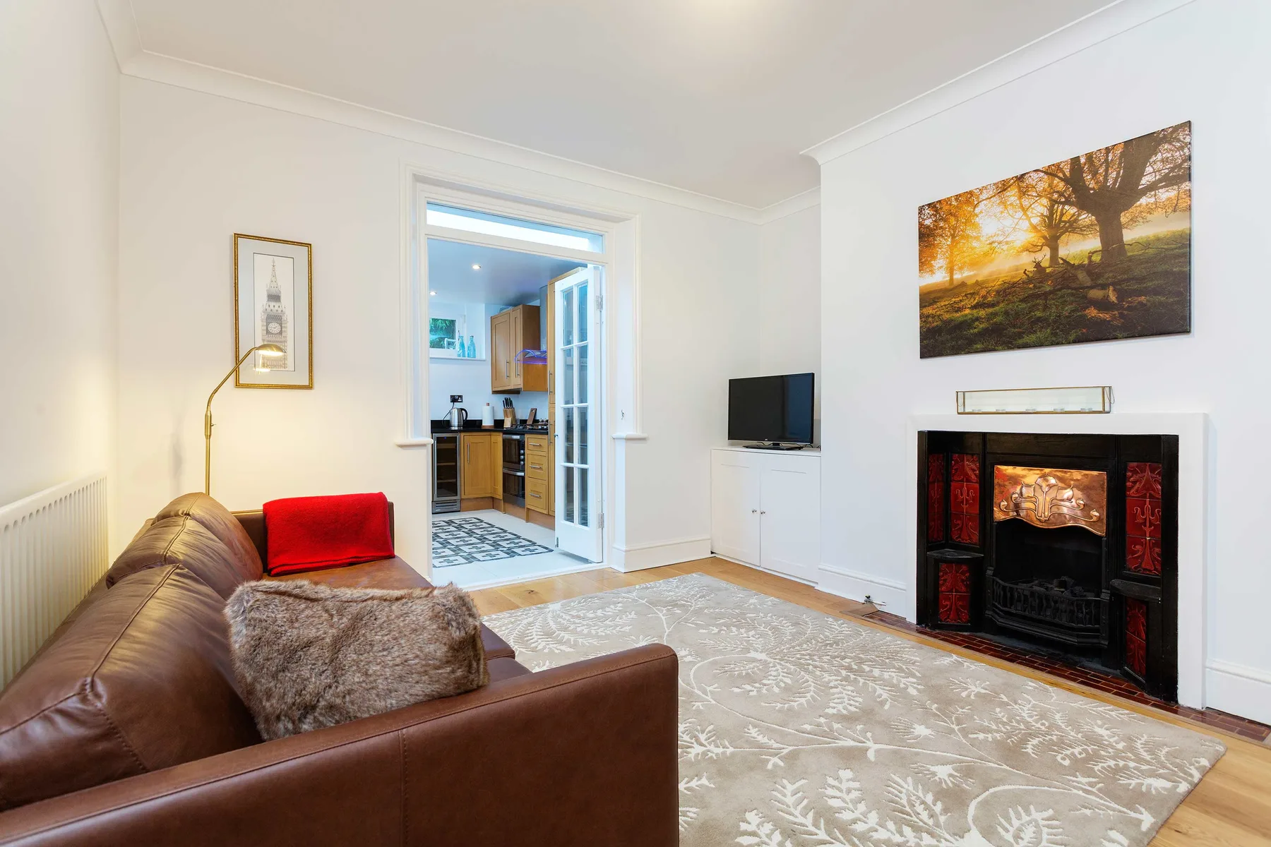 A bright living room with seating, a patterned rug, and a fireplace.