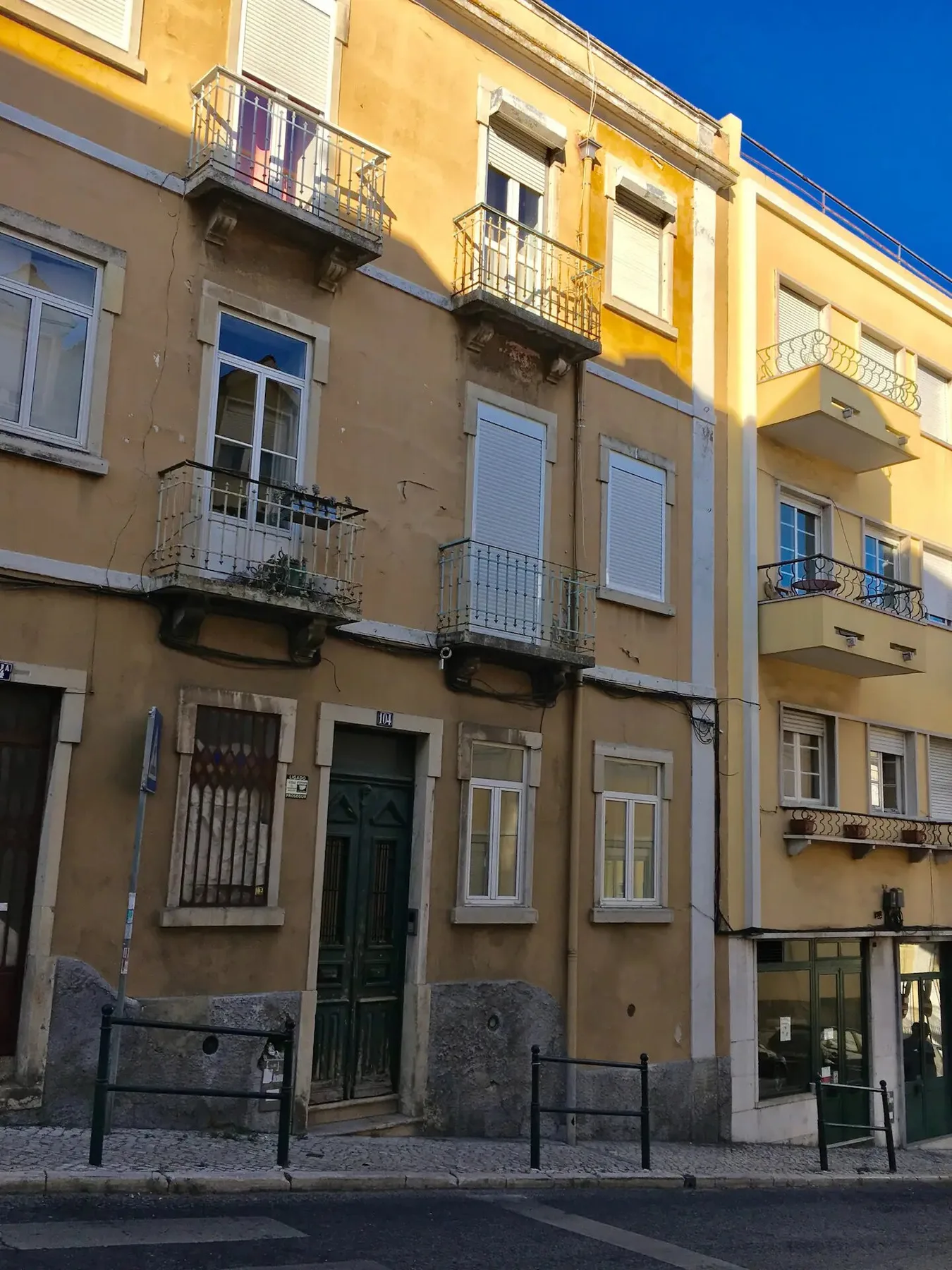 Una hilera de edificios de apartamentos con balcones en una calle soleada.