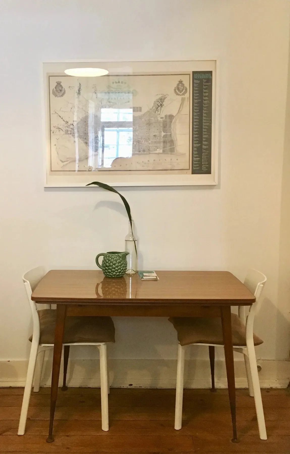 Comedor con una mesa de madera, asientos y una obra enmarcada en la pared.