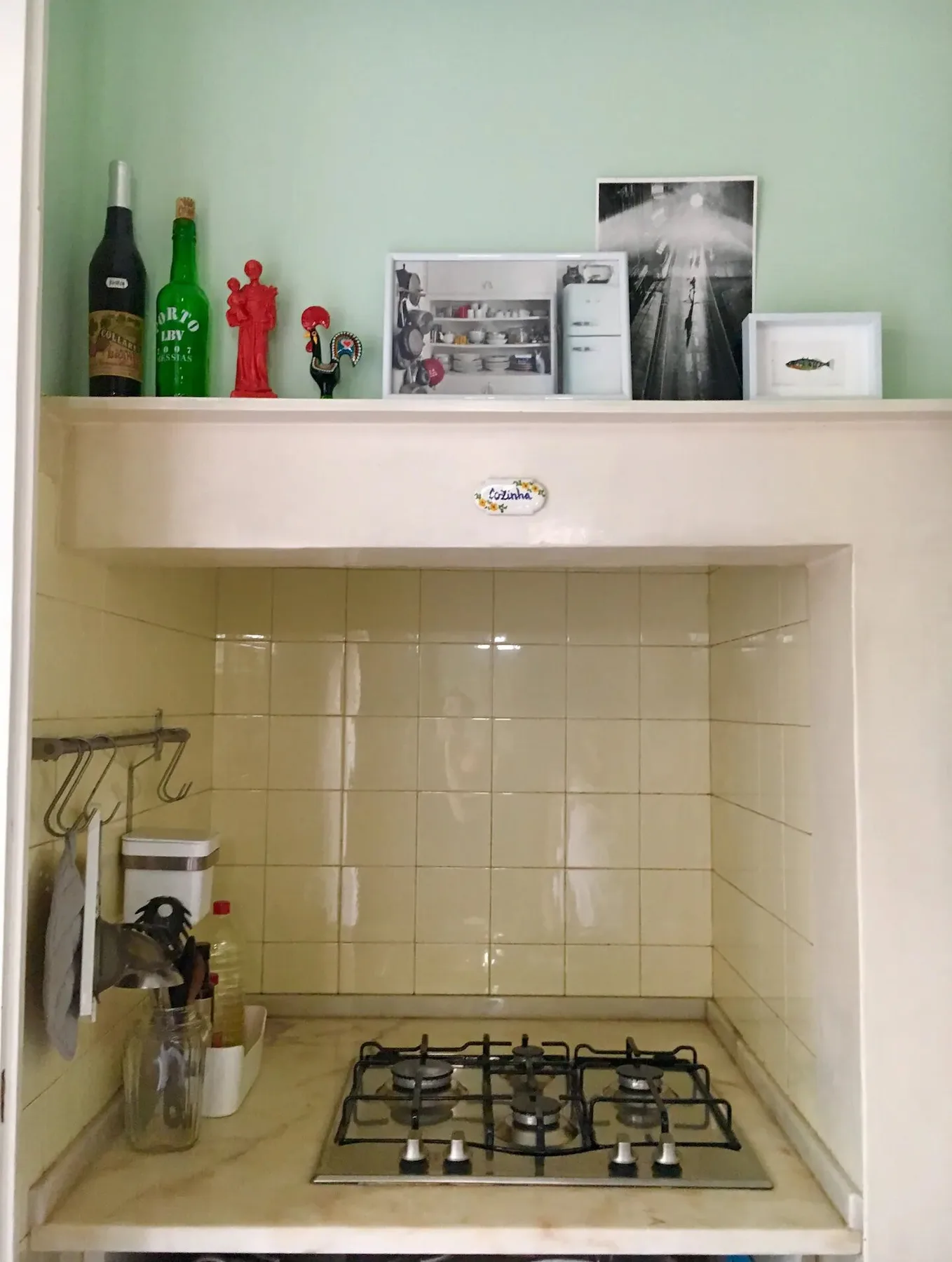Zona de cocina alicatada con una placa de gas bajo un estante.