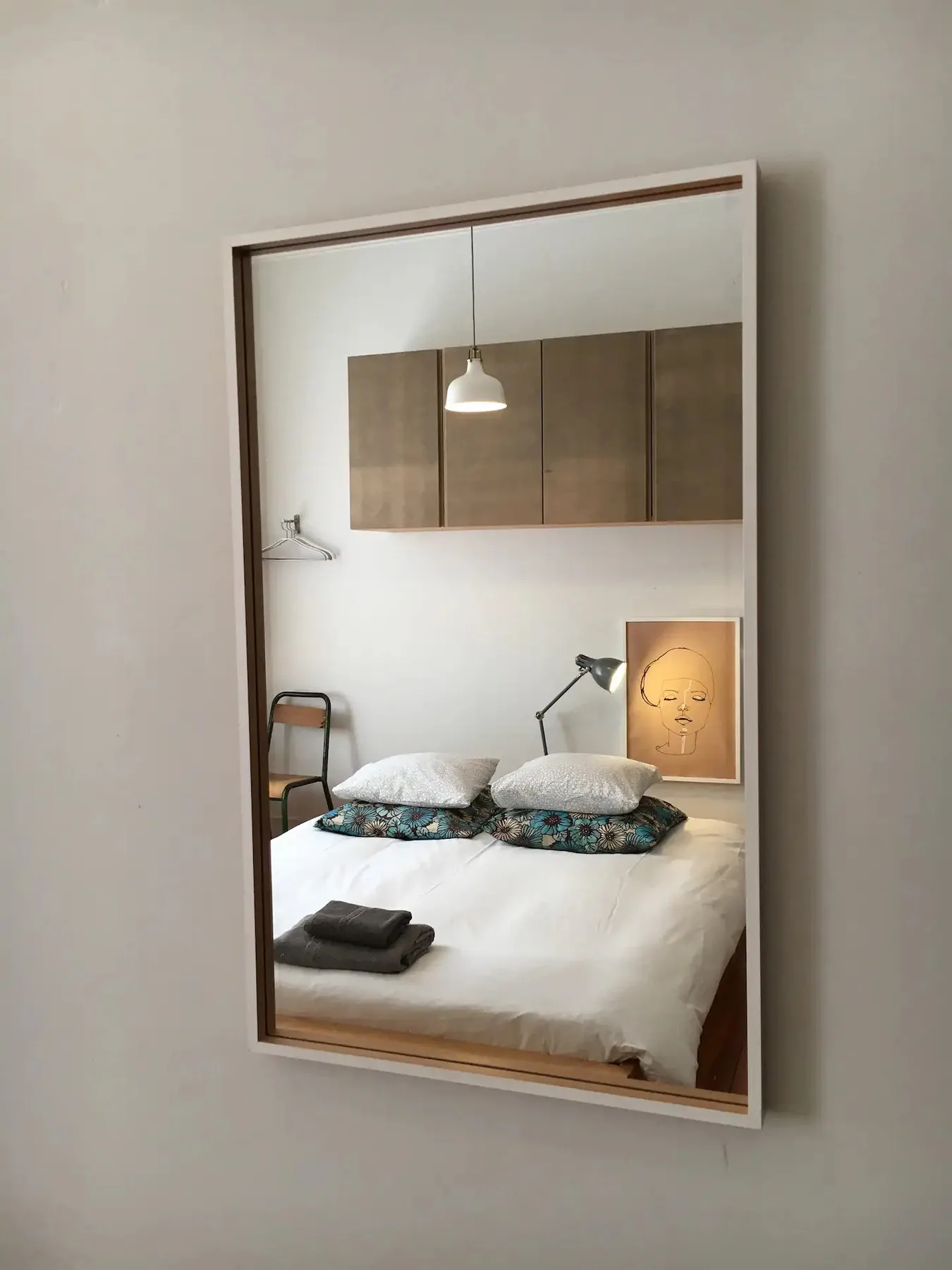 Un dormitorio con una cama bien hecha y una obra enmarcada encima.