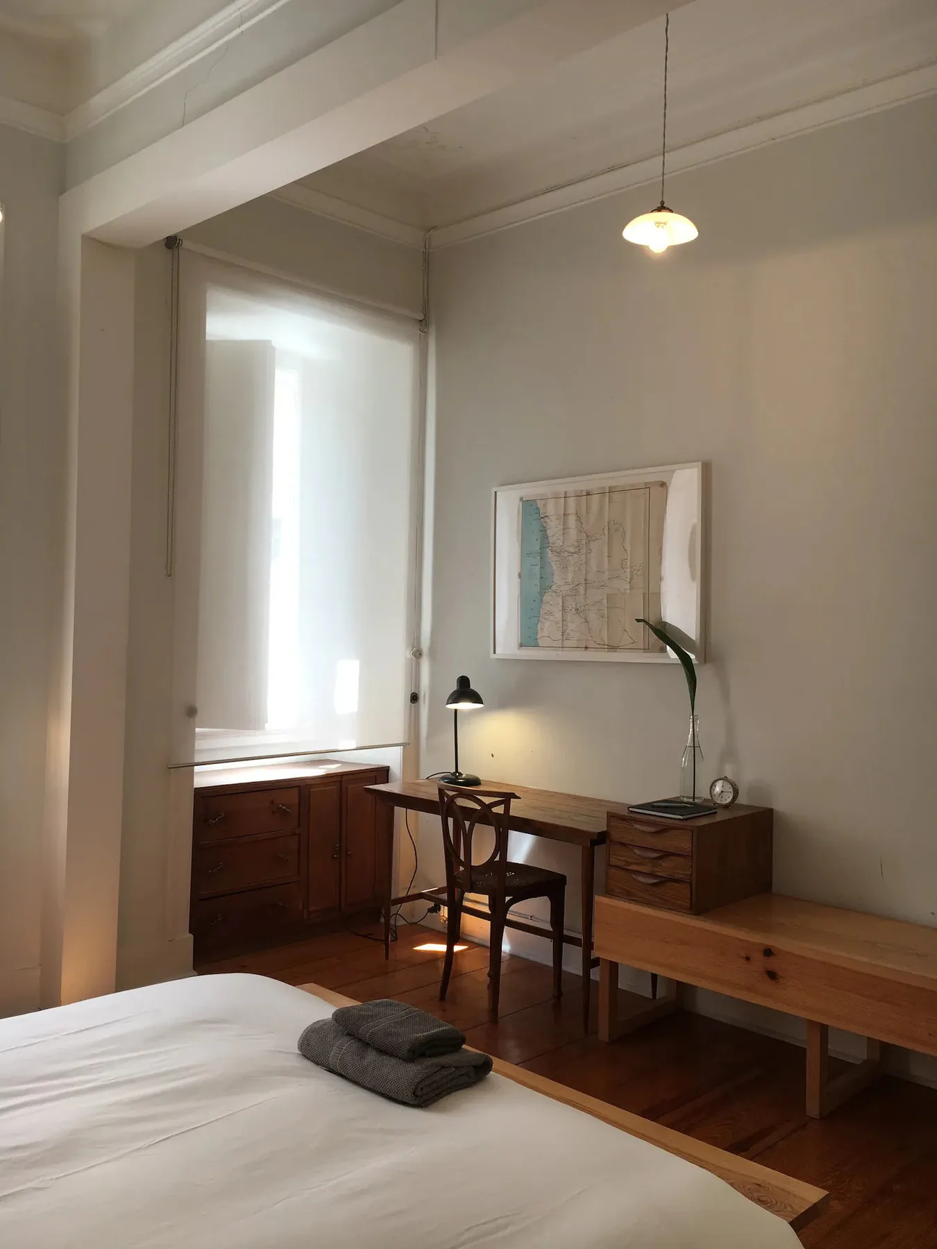 Un dormitorio con un escritorio y un banco de madera junto a la cama.