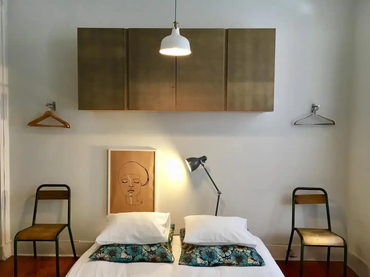 Un dormitorio con dos camas, sillas y armarios montados en la pared.