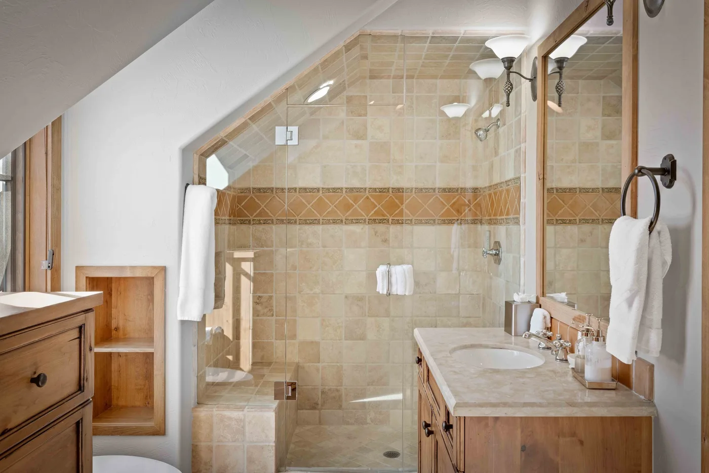 A tiled bathroom with a glass shower and a vanity.