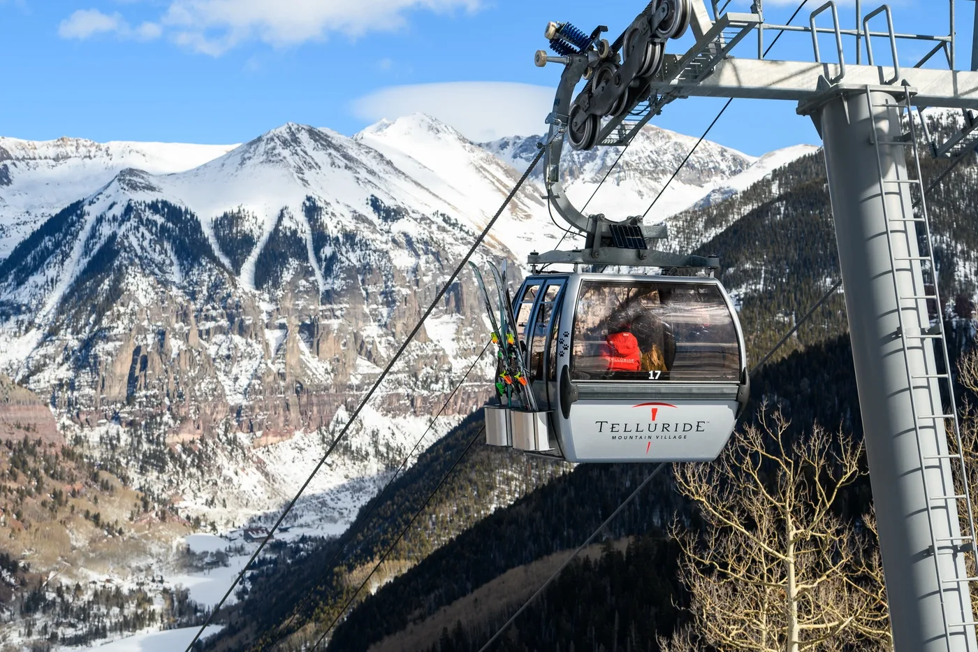 A gondola cabin travels above a snow-covered mountain valley.