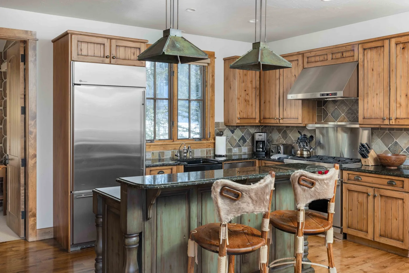 A spacious kitchen with wooden cabinets, a central island, and pendant lights.
