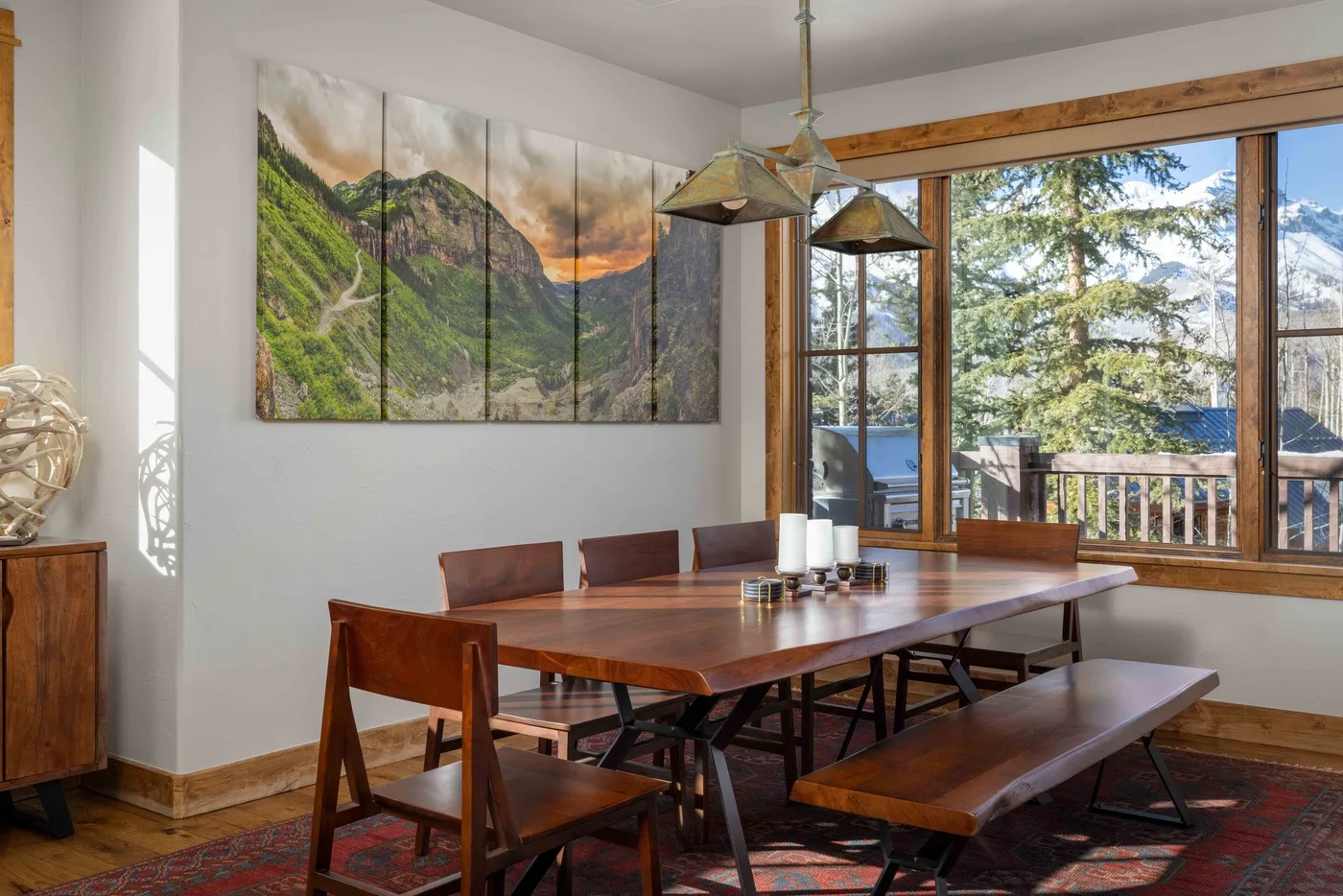 A dining area with a long wooden table and a large wall artwork.
