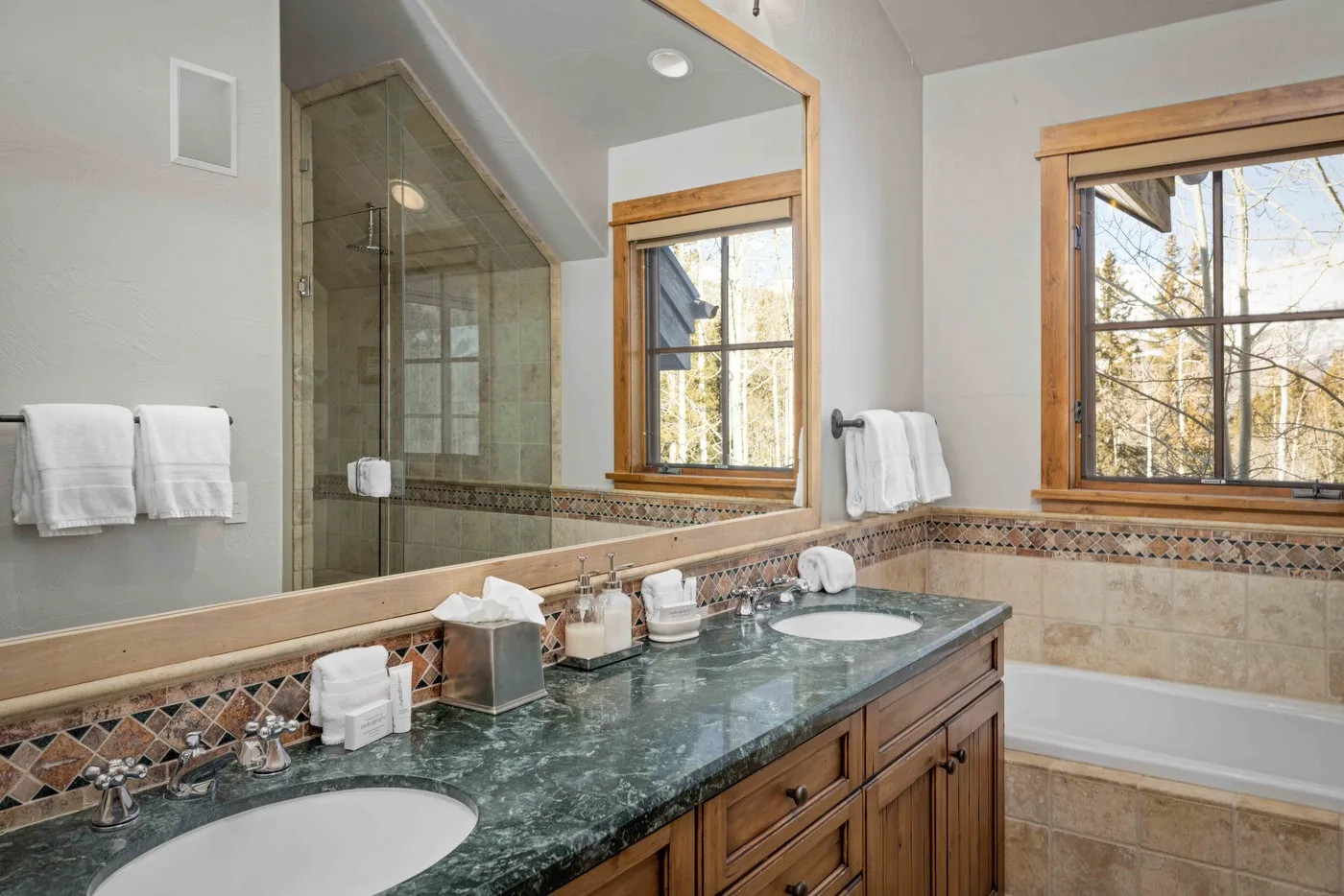 A bathroom vanity with a dark countertop sits beside a glass-enclosed shower.