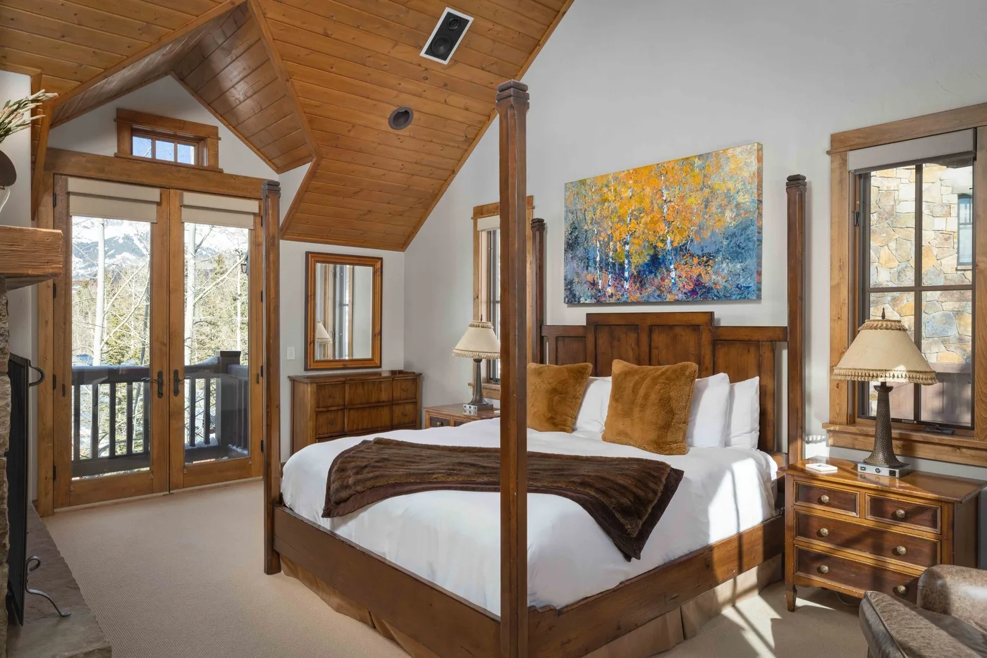 A bedroom with a wooden four-poster bed beneath a sloped wood ceiling.