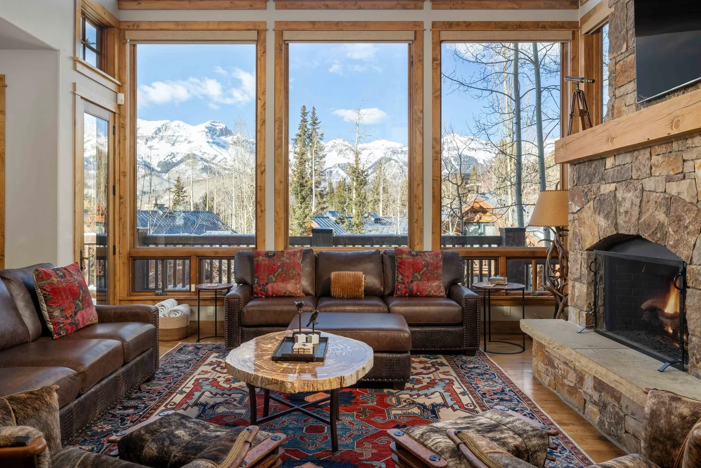 A living room with seating arranged before large windows overlooking a snowy mountain landscape.