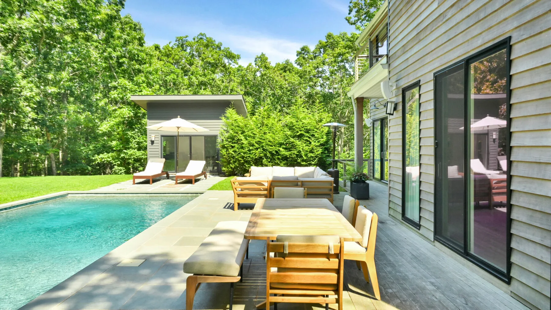 A poolside deck with outdoor seating beside a modern house.