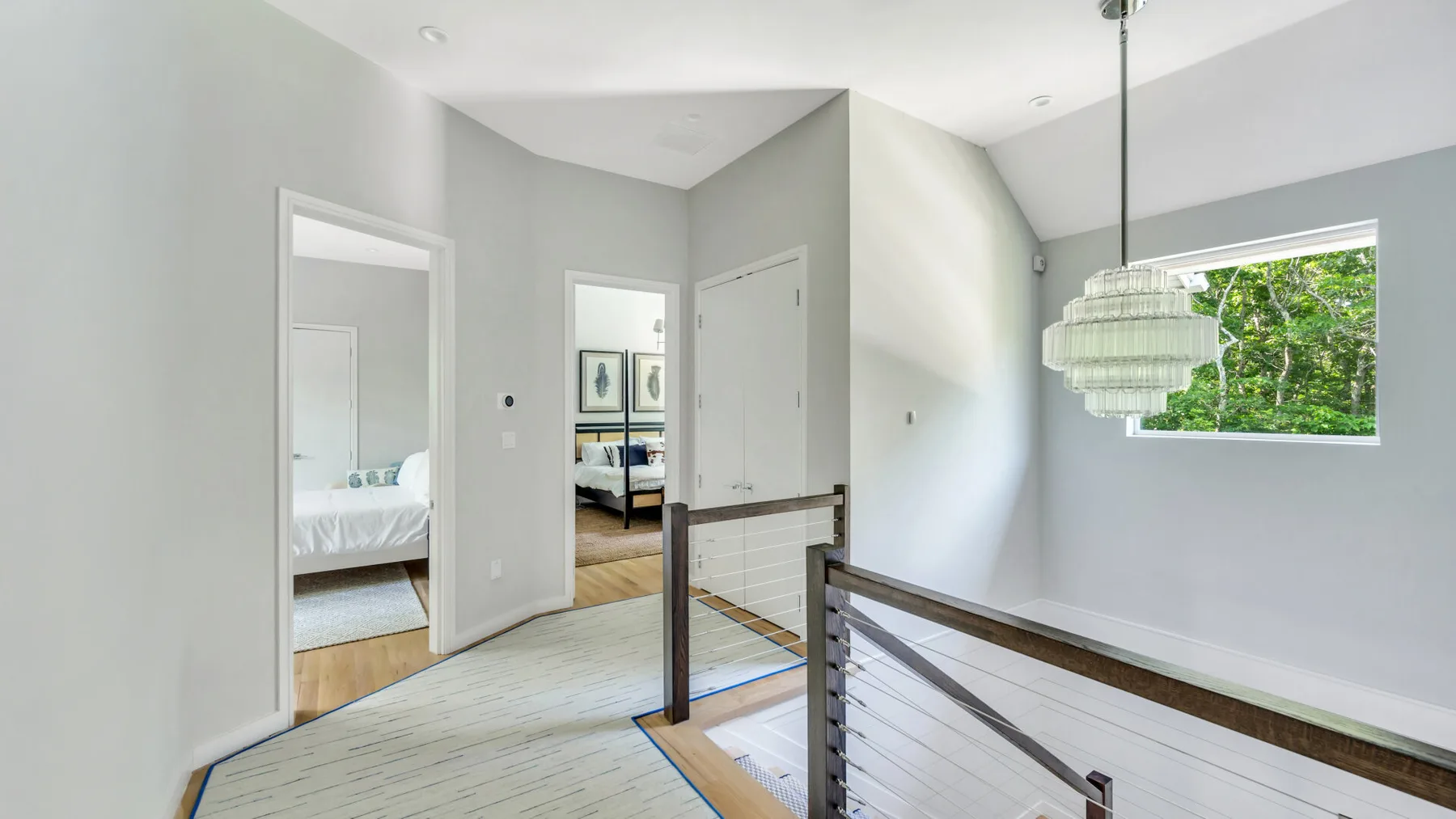 A bright upstairs landing overlooks a staircase, with a bedroom doorway and large window.
