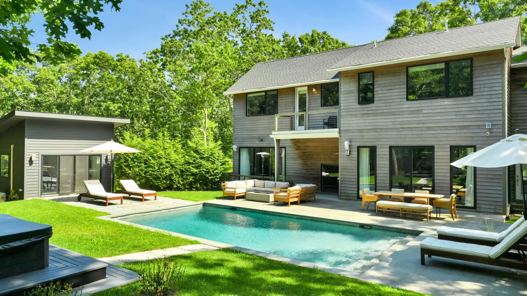 A modern house opens onto a backyard pool with outdoor seating.