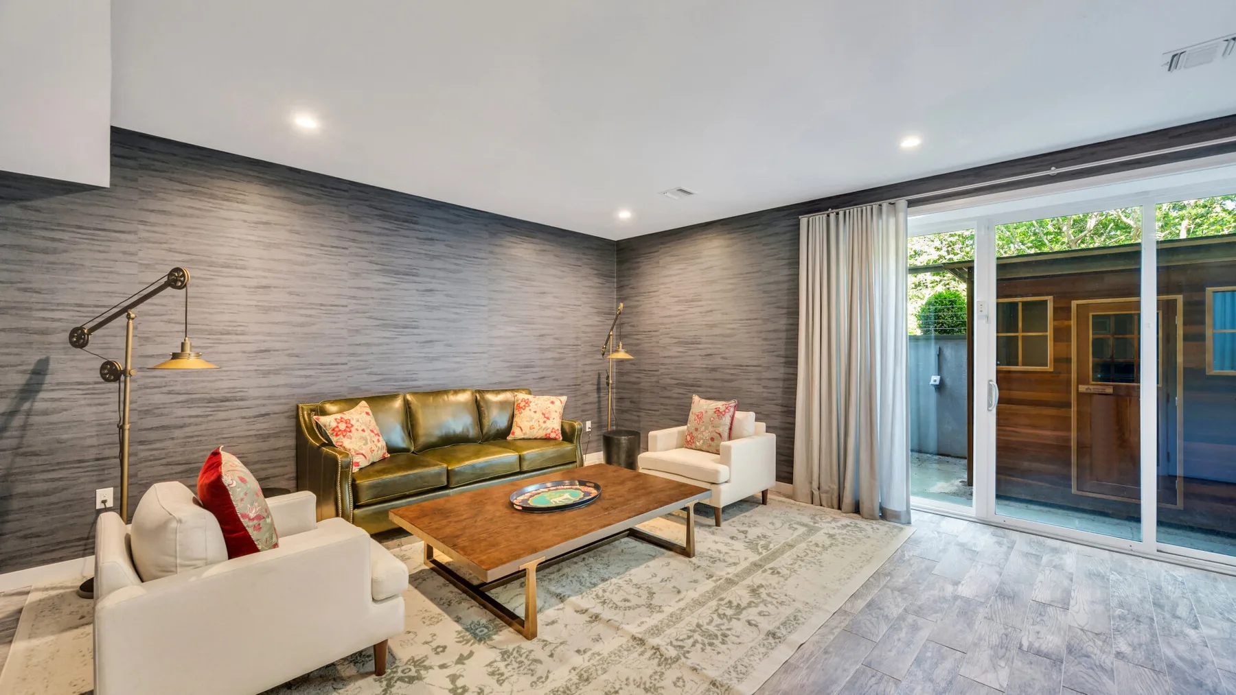 Living room with seating around a wooden coffee table beside sliding glass doors.