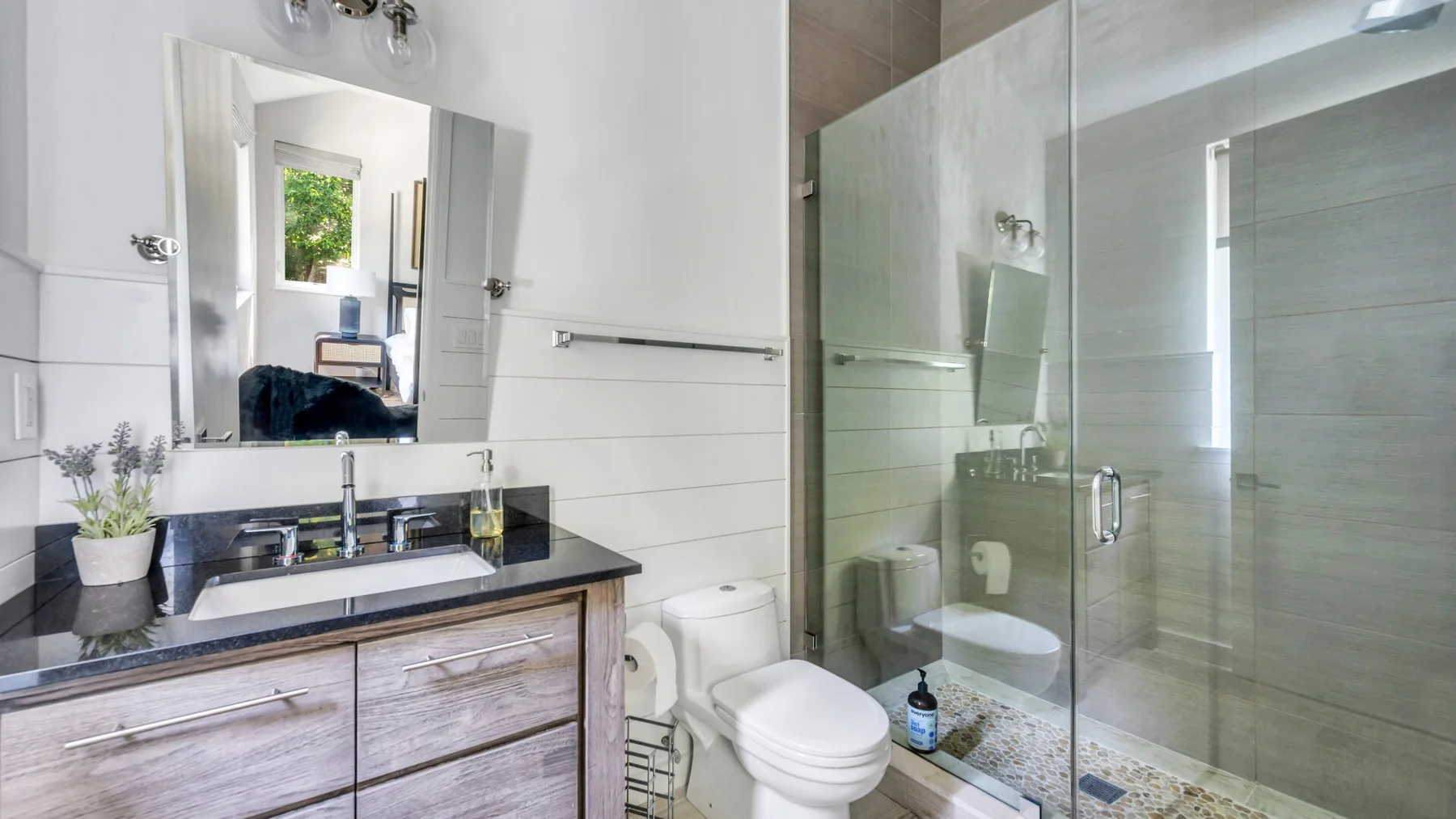 A bathroom with a vanity, sink, and glass-enclosed shower.